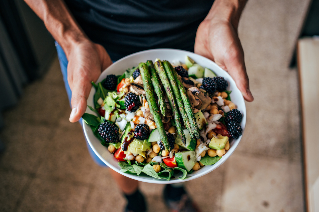 Uomo che tiene una ciotola da pranzo vegetariana Paleo